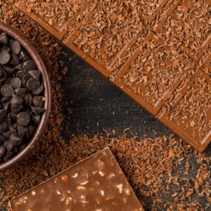 chocolate crumbs with choco bars, choco drops on dark background, flat lay.