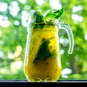 front view invigorating lemonade in decanter with lemon lime and spinach