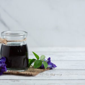 a glass of butterfly pea flower tea put on white wooden floor