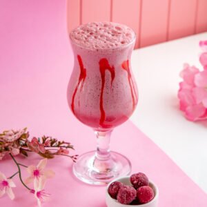 side view raspberry milkshake with cream milk and frozen raspberries on the table