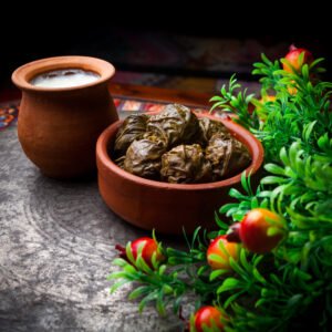 side view dolma with yogurt and vinegar in a clay plate on wooden background