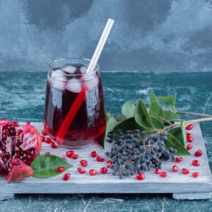 a sliced of pomegranate and juice on the board , on the blue background