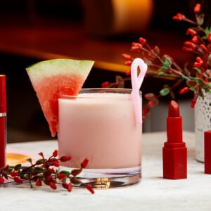 watermelon milkshake garnished with watermelon, next to red lipstick